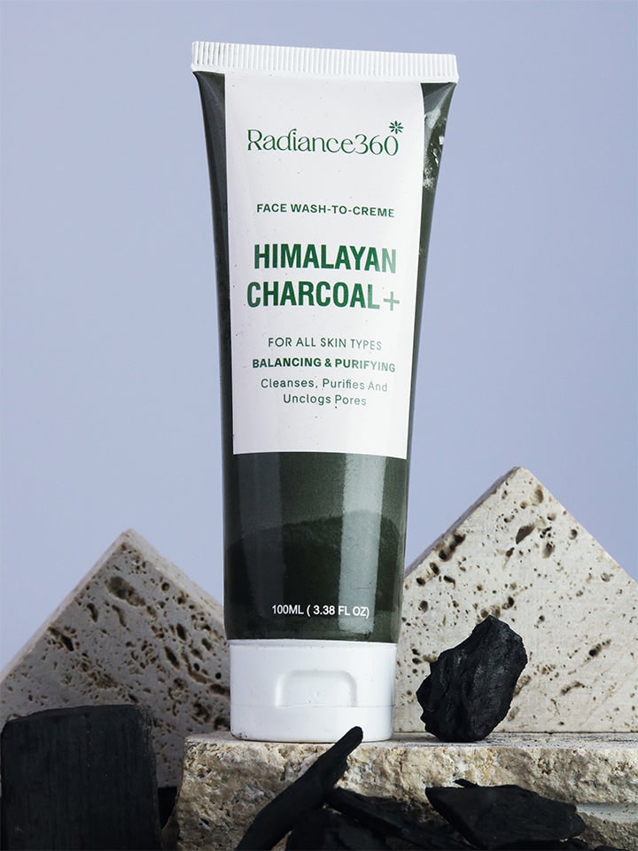 Radiance360 Himalayan Charcoal face wash tube on a stone surface with charcoal pieces.