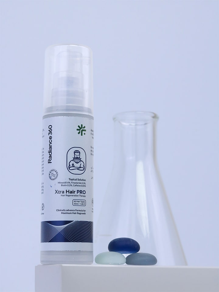 Bottle of Xtra Hair PRO with a beaker and stones on a light gray background